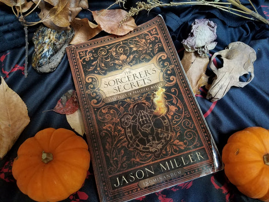 Jason Miller's The Sorcerer's Secrets book on an altar with pumpkins.