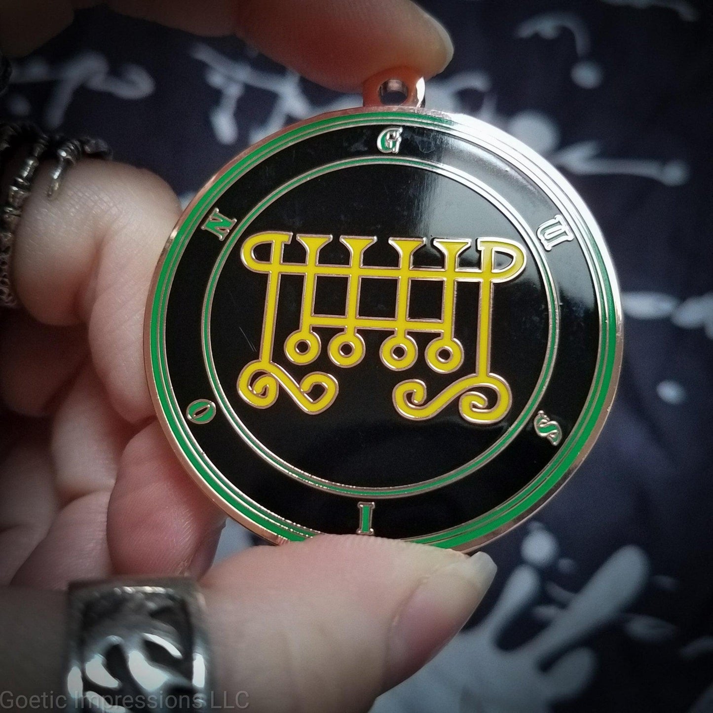 Talisman of goetic spirit Gusion. Gusion's sigil is yellow with the circles surrounding in green along with the name on a black background.
