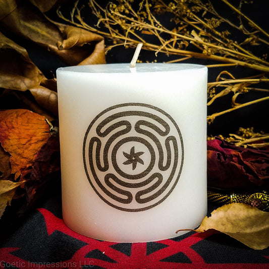 A while candle with a black imprinted design of the Stropholos or Wheel of Hecate