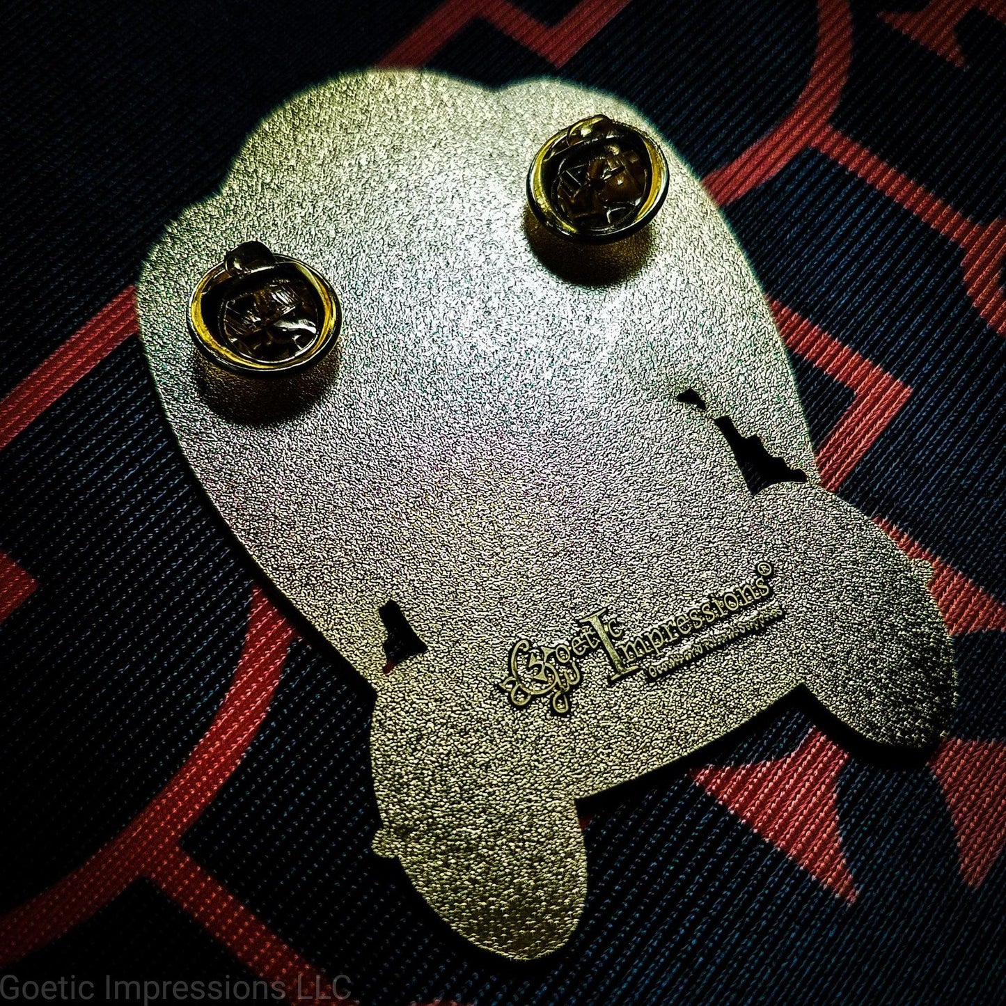 Back of a Belial pin. The pin is stamped with Goetic Impressions with two pin clutches.