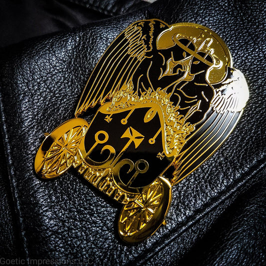 Black and gold hard enamel pin featuring the demon Belial. Belial is shown as two angels facing each other with arms interlocked.  They are standing in a flaming chariot.  The pin is on a black jacket. 