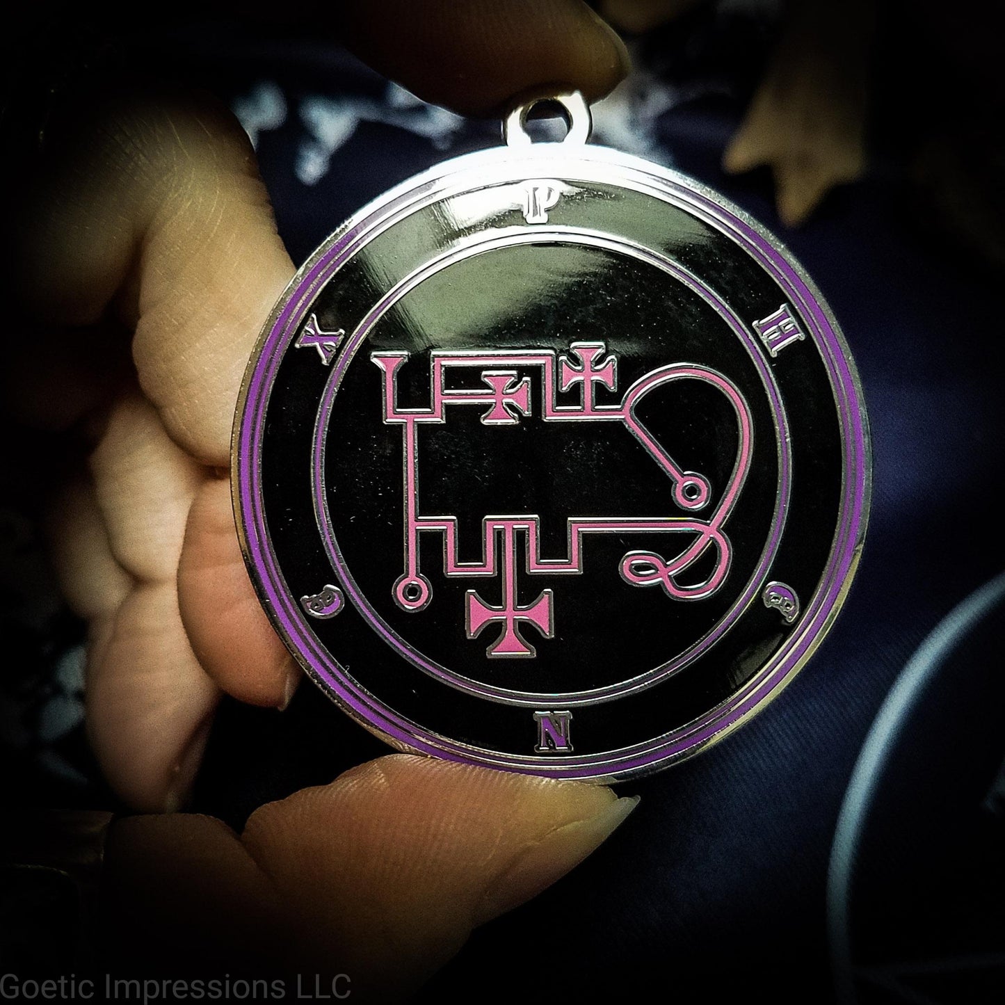Talisman of goetic spirit Phenex. Phenex's sigil is pink with the circles surrounding in purple along with the name on a black background.