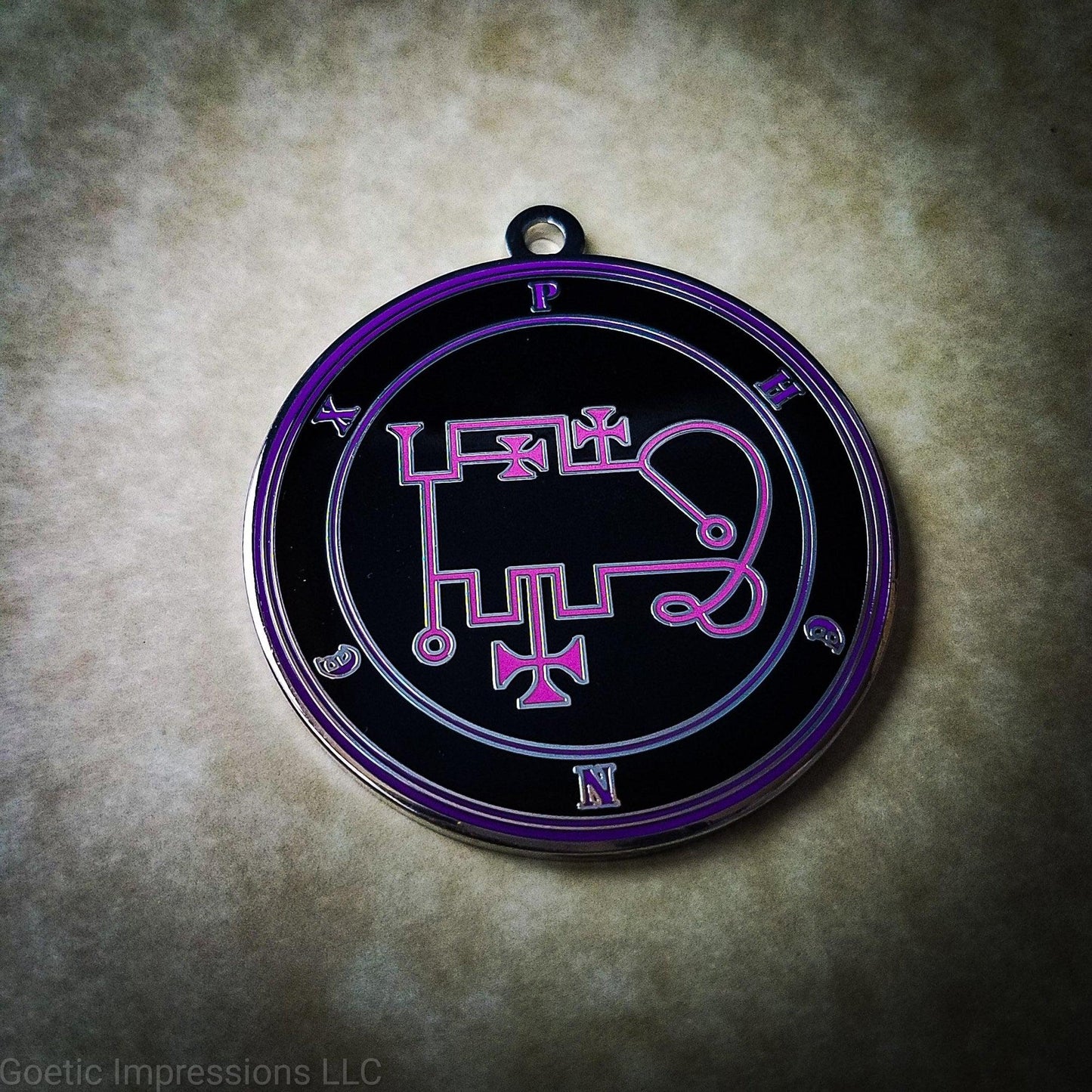 Talisman of goetic spirit Phenex. Phenex's sigil is pink with the circles surrounding in purple along with the name on a black background.
