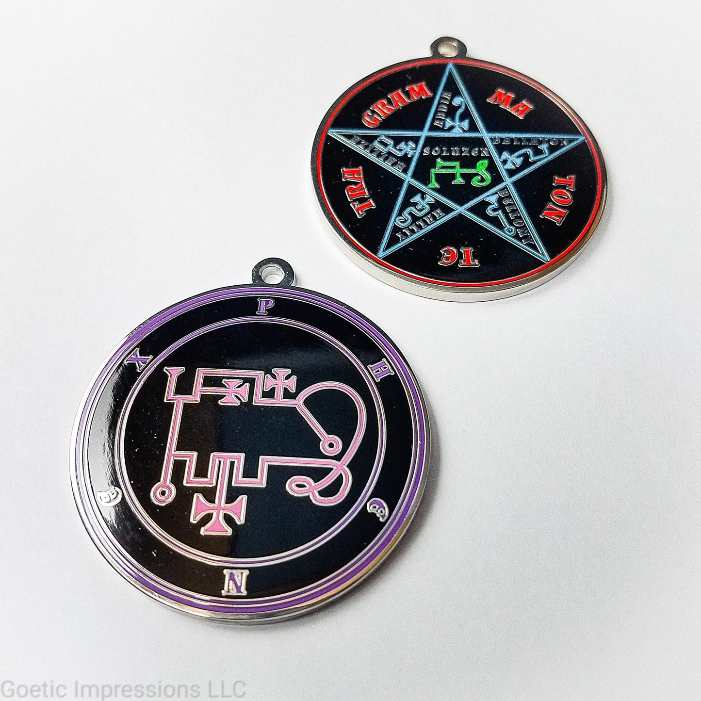 Two silver plated medallions featuring the front and back of the Ars Goetia spirit Phenex. The sigil is pink with the name and circle surrounding in purple. The Reverse is the TETRAGRAMMATON. The pentacle is blue with a red circle. Tetragrammaton is in red. The center sigil is green.