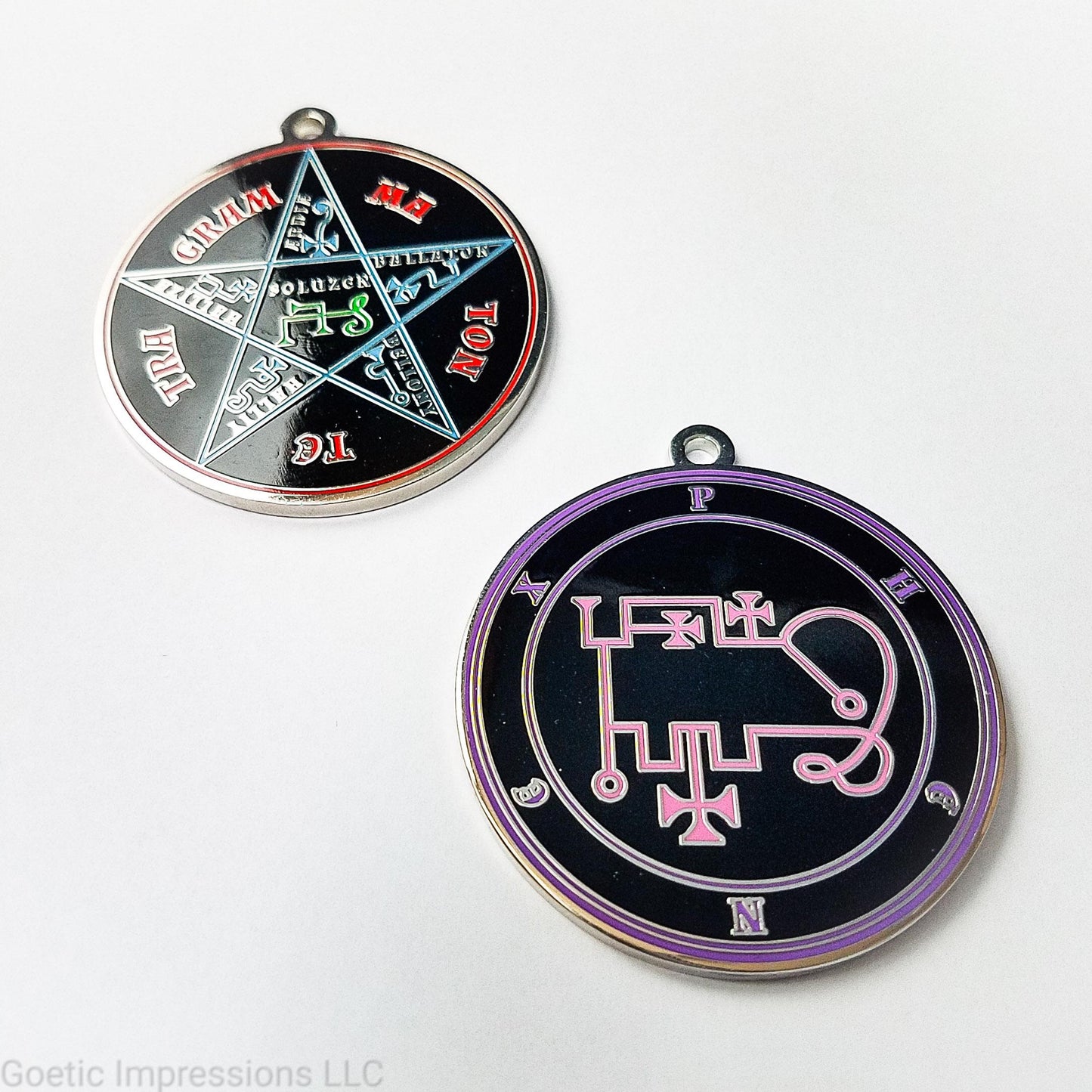 Two silver plated medallions featuring the front and back of the Ars Goetia spirit Phenex. The sigil is pink with the name and circle surrounding in purple. The Reverse is the TETRAGRAMMATON. The pentacle is blue with a red circle. Tetragrammaton is in red. The center sigil is green.