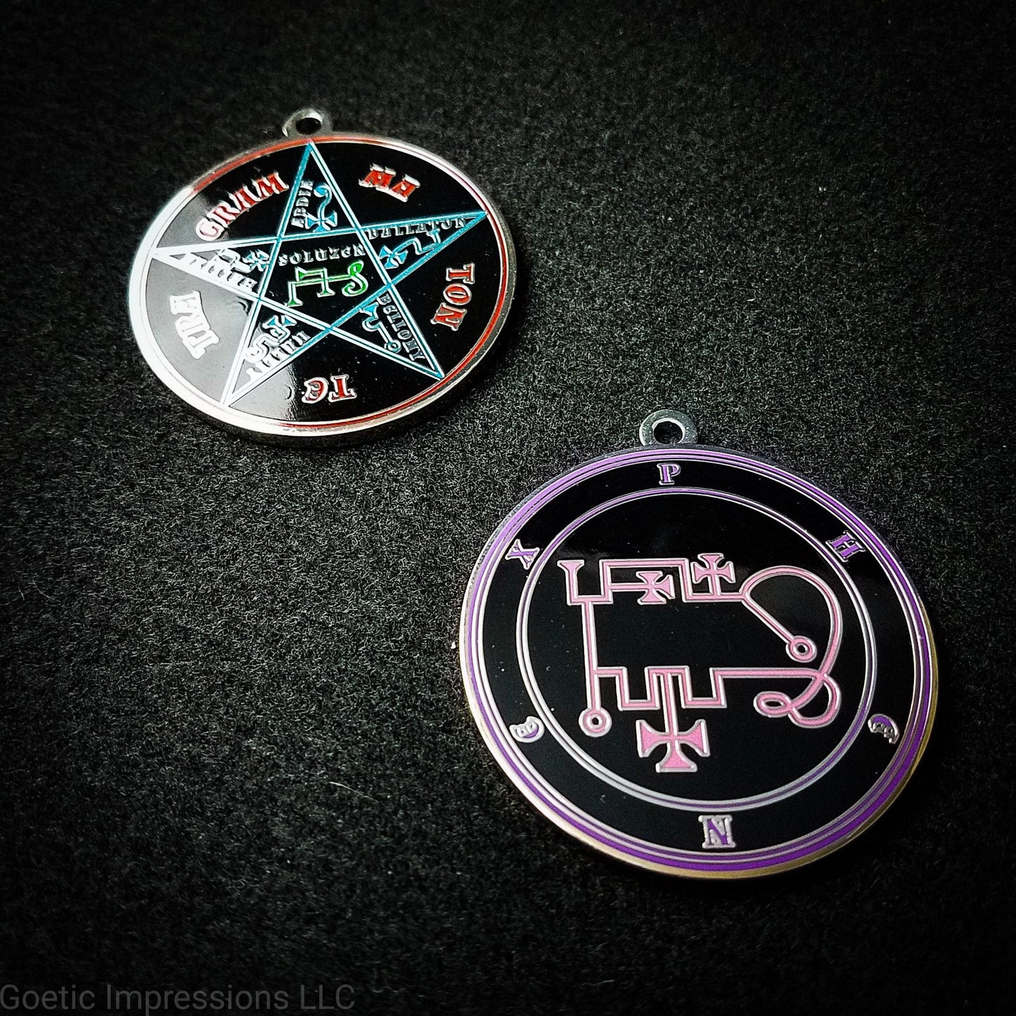 Two silver plated medallions featuring the front and back of the Ars Goetia spirit Phenex. The sigil is pink with the name and circle surrounding in purple. The Reverse is the TETRAGRAMMATON. The pentacle is blue with a red circle. Tetragrammaton is in red. The center sigil is green.