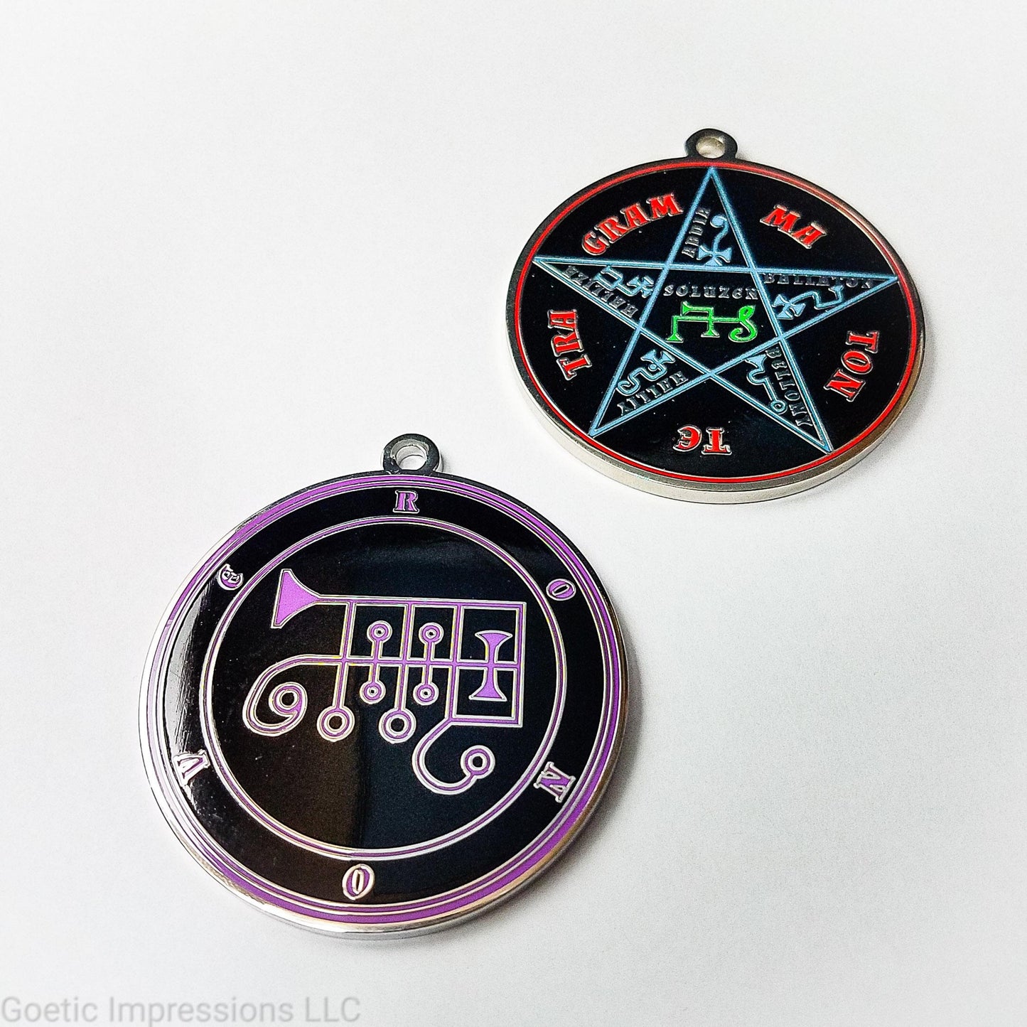 Two silver plated medallions featuring the front and back of the Ars Goetia spirit Ronove. The sigil is purple with the name and circle surrounding in purple. The Reverse is the TETRAGRAMMATON. The pentacle is blue with a red circle. Tetragrammaton is in red. The center sigil is green.