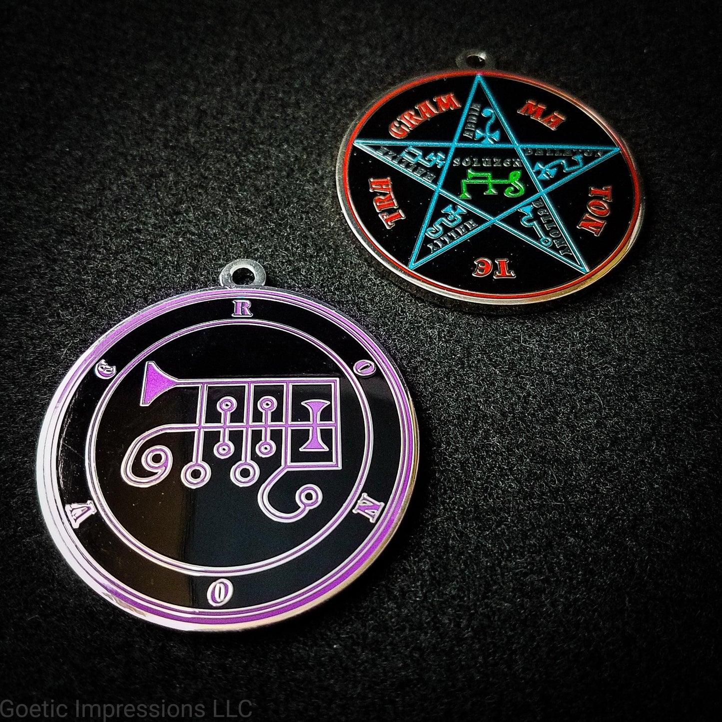 Two silver plated medallions featuring the front and back of the Ars Goetia spirit Ronove. The sigil is purple with the name and circle surrounding in purple. The Reverse is the TETRAGRAMMATON. The pentacle is blue with a red circle. Tetragrammaton is in red. The center sigil is green.