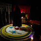 A magician standing in the center of a 9ft magickal circle of solomon with candles lit on each corner. The magician is looking into the triangle of solomon.