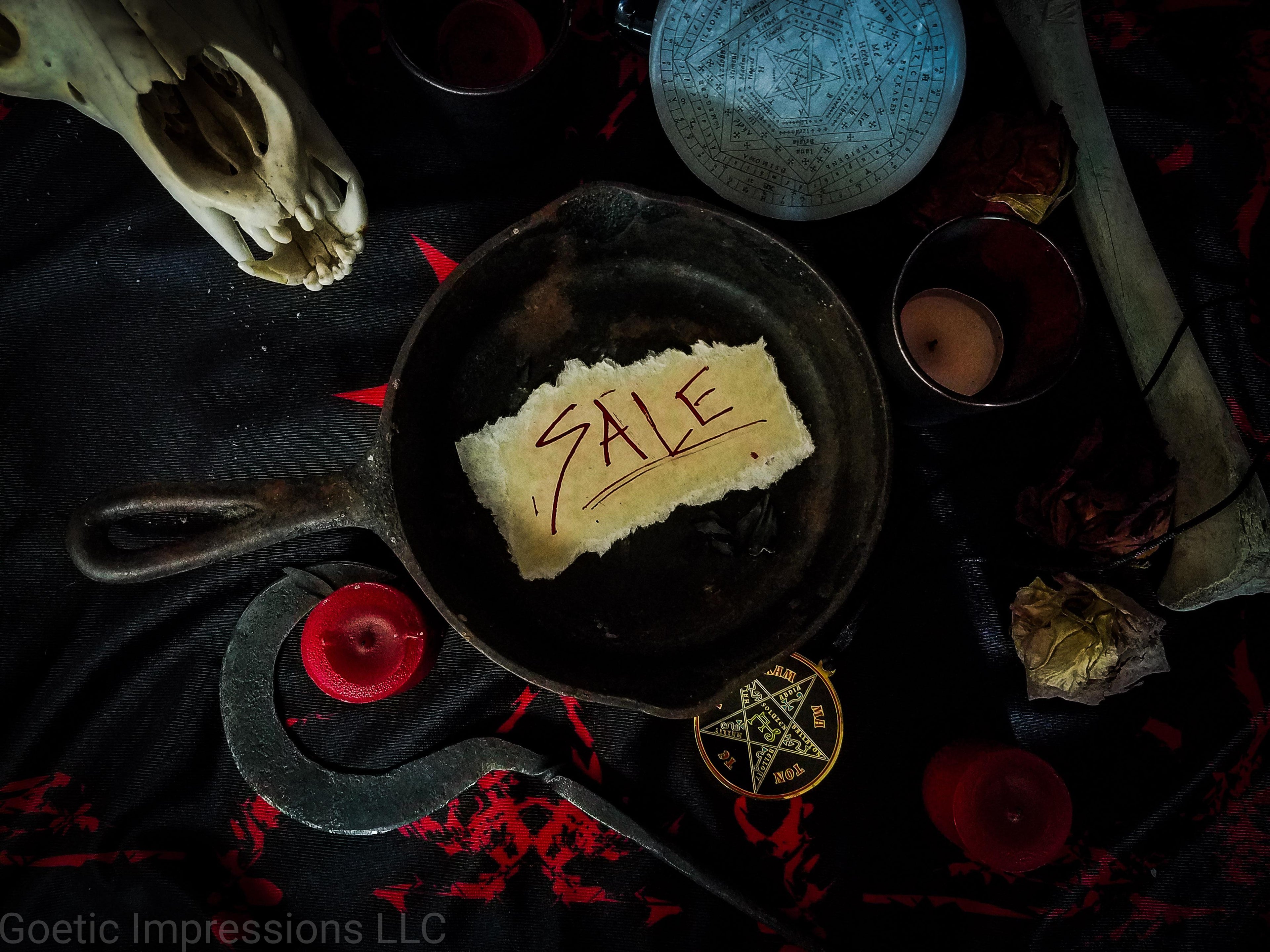 Altar setup with a cast iron pan in the center with a SALE sign inside it.