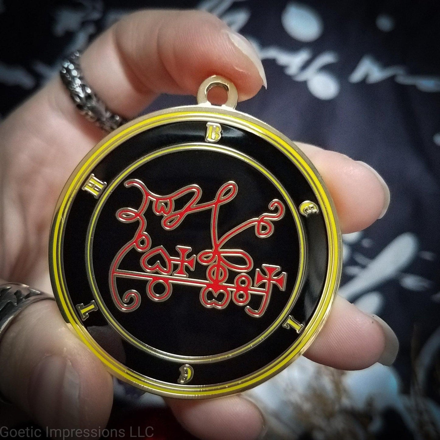 Amulet of Beleth. The sigil for Beleth is red. Beleth's name is surrounding the sigil with concentric circles in yellow on a black background. The seal is gold plated.