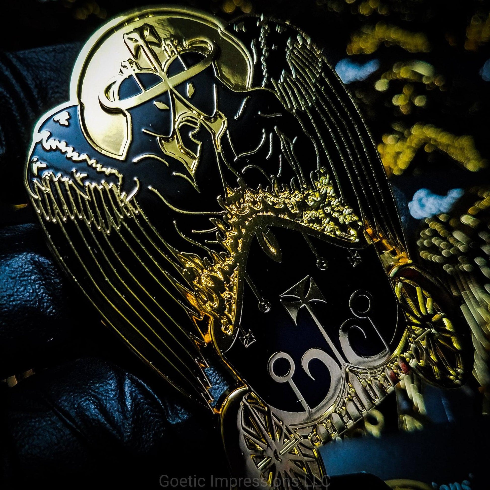 Black and gold hard enamel pin featuring the demon Belial. Belial is shown as two angels facing each other with arms interlocked.  They are standing in a flaming chariot. 