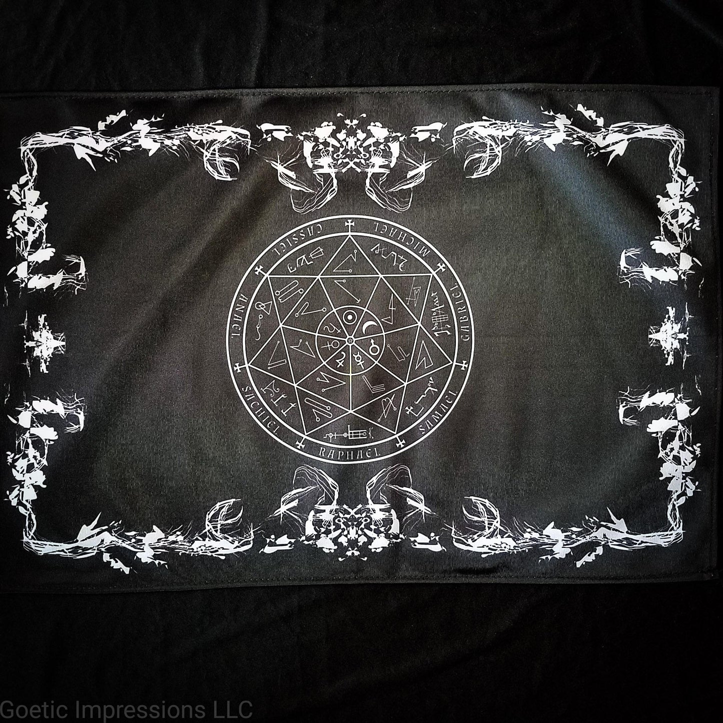 A black and white altar cloth with a seal of the planetary Archangels in the center. The seal contains various astrological sigils.