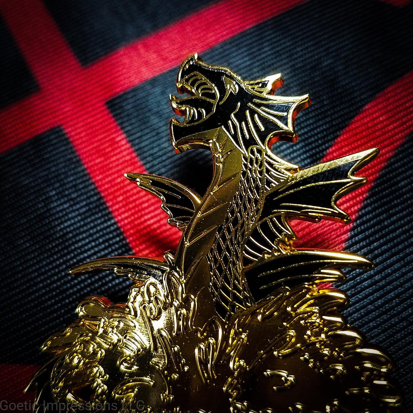 A black and gold hard enamel pin of the sea serpent Leviathan. Leviathan is shown bursting from waters and jaws wide open. The pin is on an altar black and red altar cloth with Levithan's sigil on it.