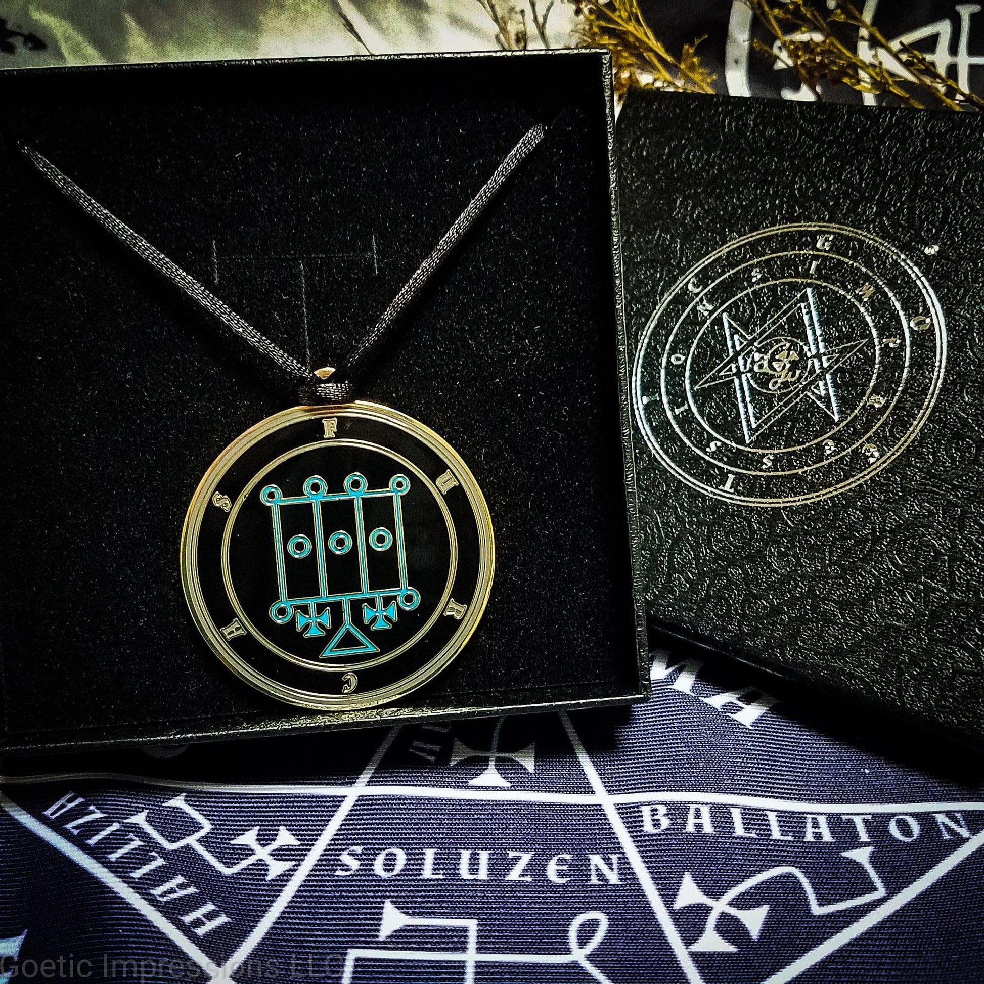 Necklace of Furcas in a Goetic Impressions gift box stamped in silver foil. The sigil for Furcas is blue. Furcas's name is surrounding the sigil with concentric circles in gray on a black background. The seal is brass plated. The box is on a purple altar cloth with the Tetragrammaton in white.