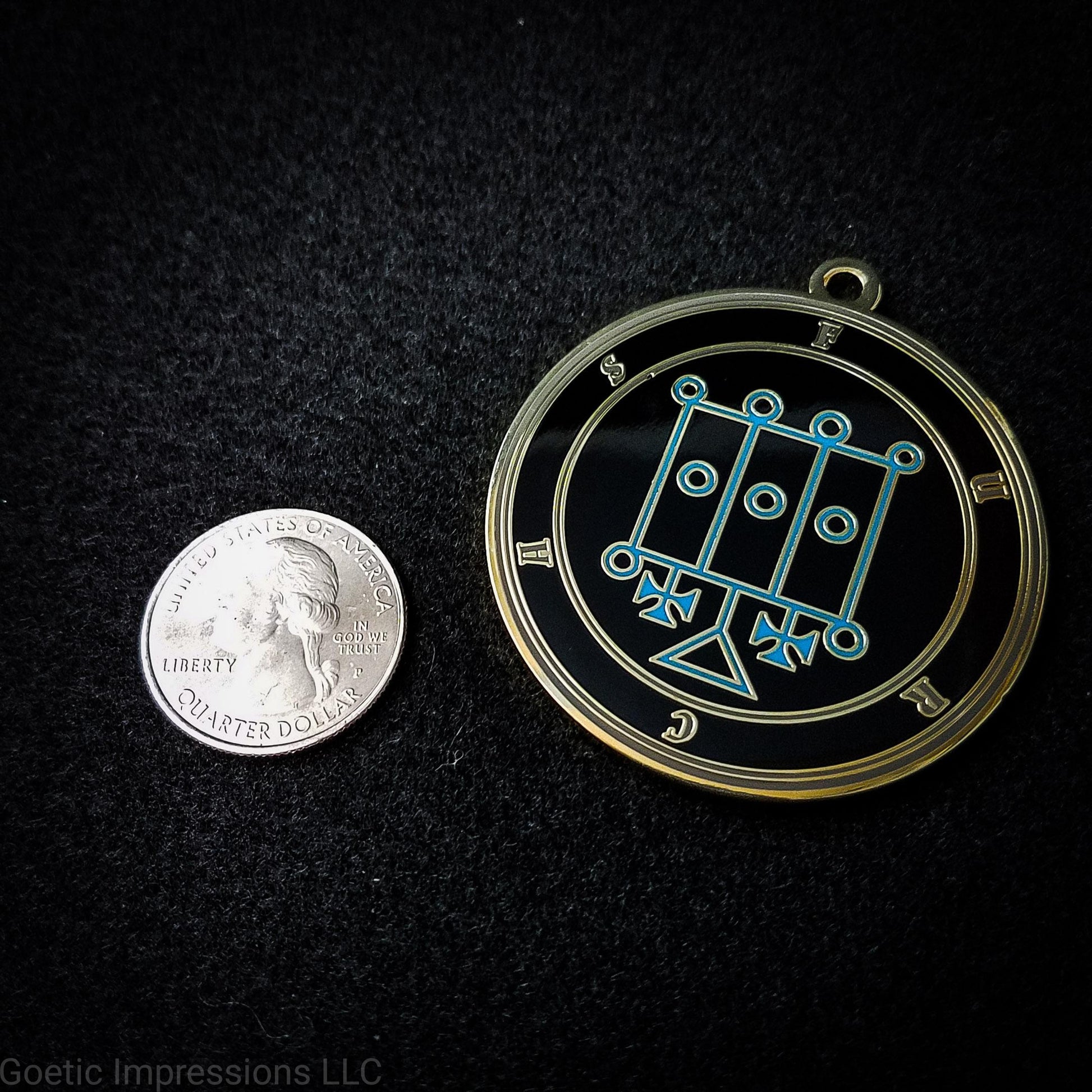 Seal of Furcas next to a quarter. The seal medallion measures two inches in diameter. The sigil is blue with gray letters and circles on a black background. 