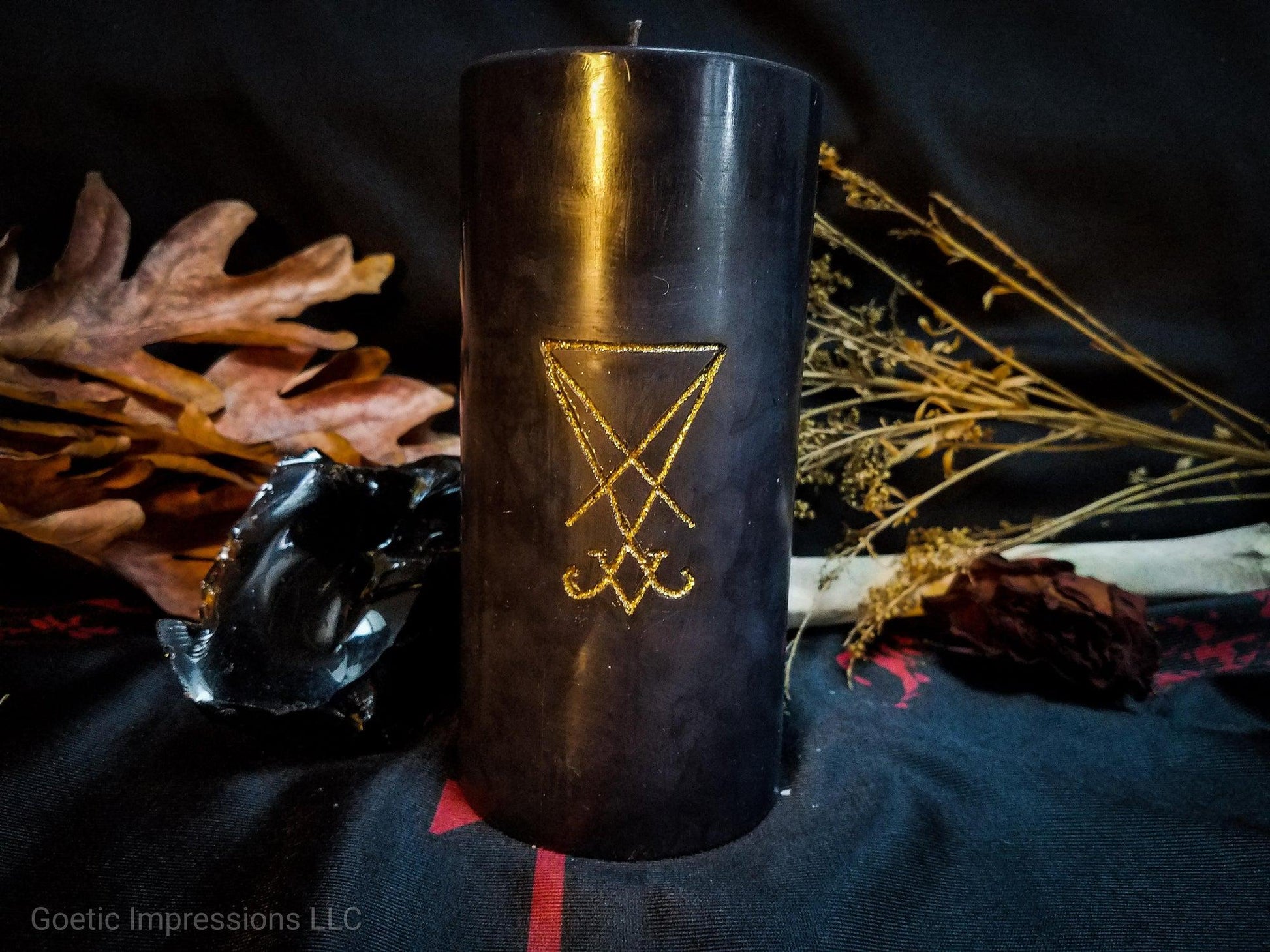 Black pillar candle with a gold Lucifier sigil carved into it.