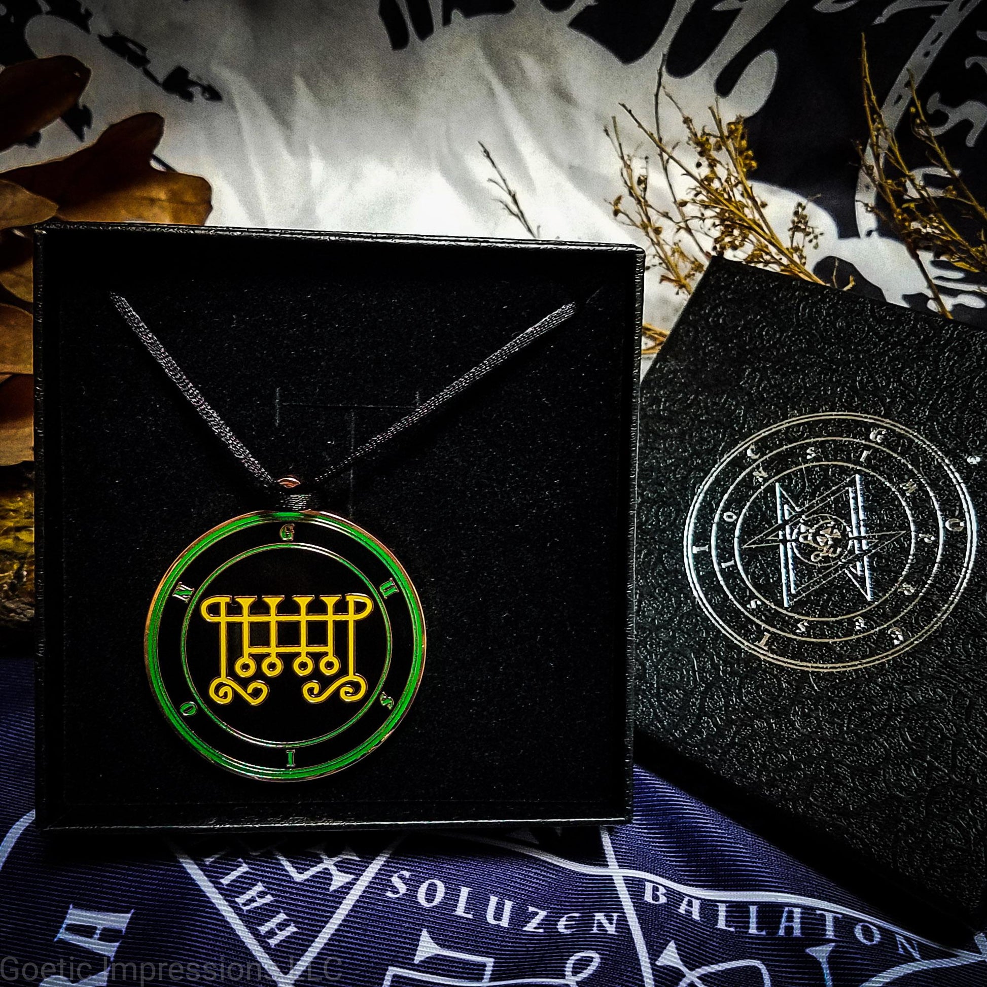 Necklace of Gusion in a Goetic Impressions gift box stamped in silver foil. The sigil for Gusion is yellow. Gusion's name is surrounding the sigil with concentric circles in green on a black background. The seal is copper plated. The box is on a purple altar cloth with the Tetragrammaton in white.