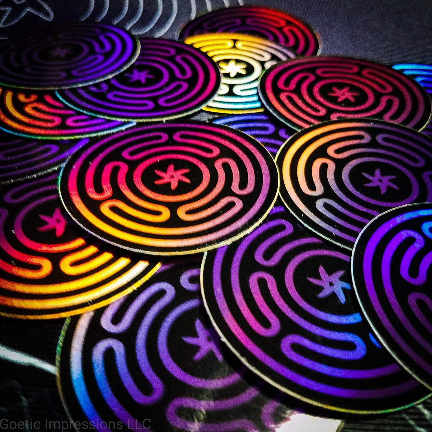 A pile of Holographic stickers featuring the wheel of Hecate or Stropholos. The base color of the sigil is purple on a black background.