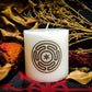 A while candle with a black imprinted design of the Stropholos or Wheel of Hecate