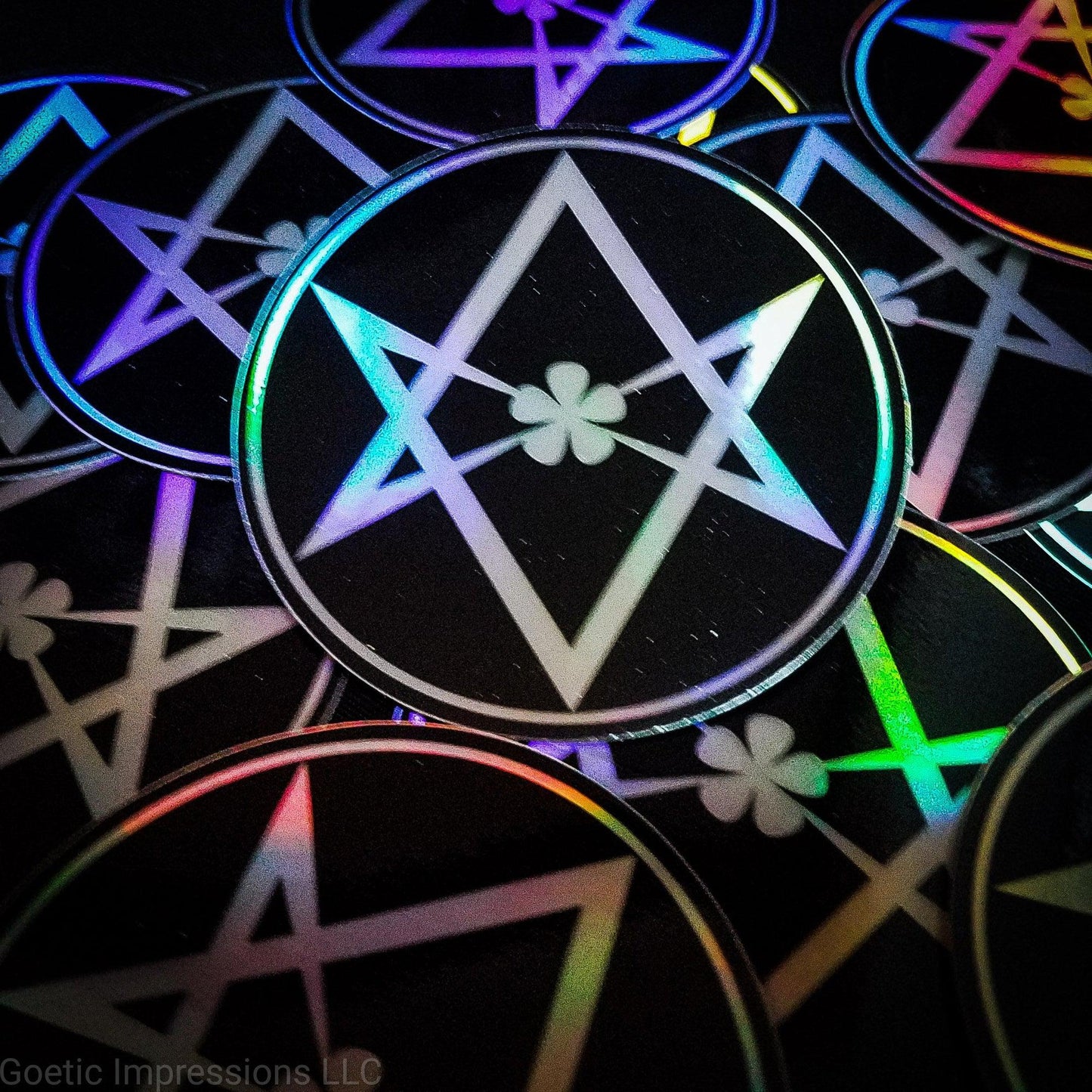 A pile of holographic stickers featuring a black and white sticker of the Unicursal Hexagram. The sticker is circular 