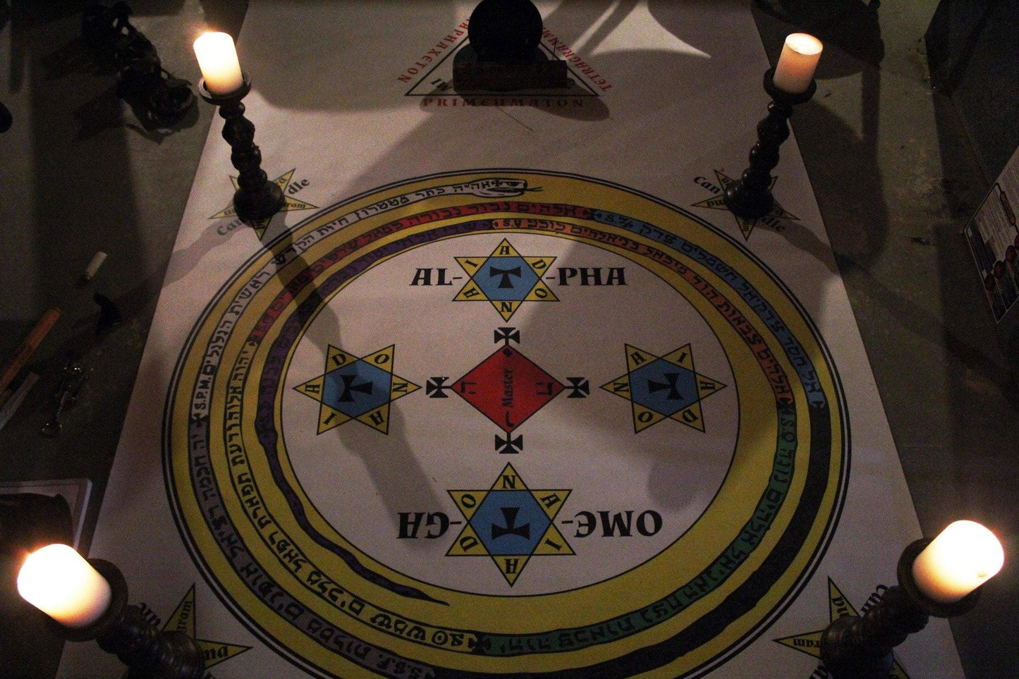 A setup of a goetic working with candles and black mirror with the goetic evocation summoning circle mat.