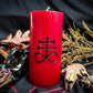 Red pillar candle with a black Leviathan cross carved into it.