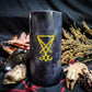 Black pillar candle with a yellow sigil of lucifer carved into it.