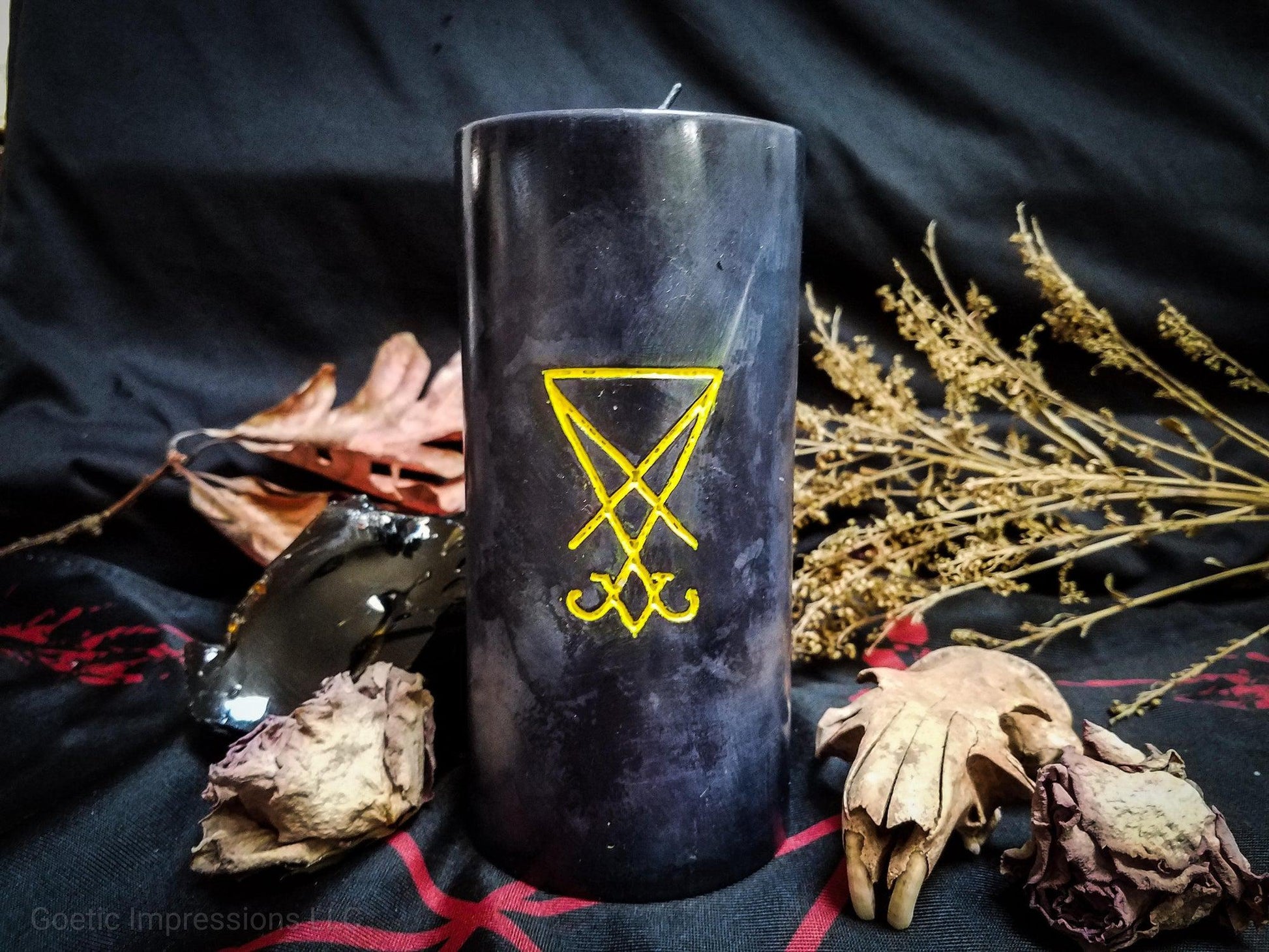 Black pillar candle with a yellow sigil of lucifer carved into it.