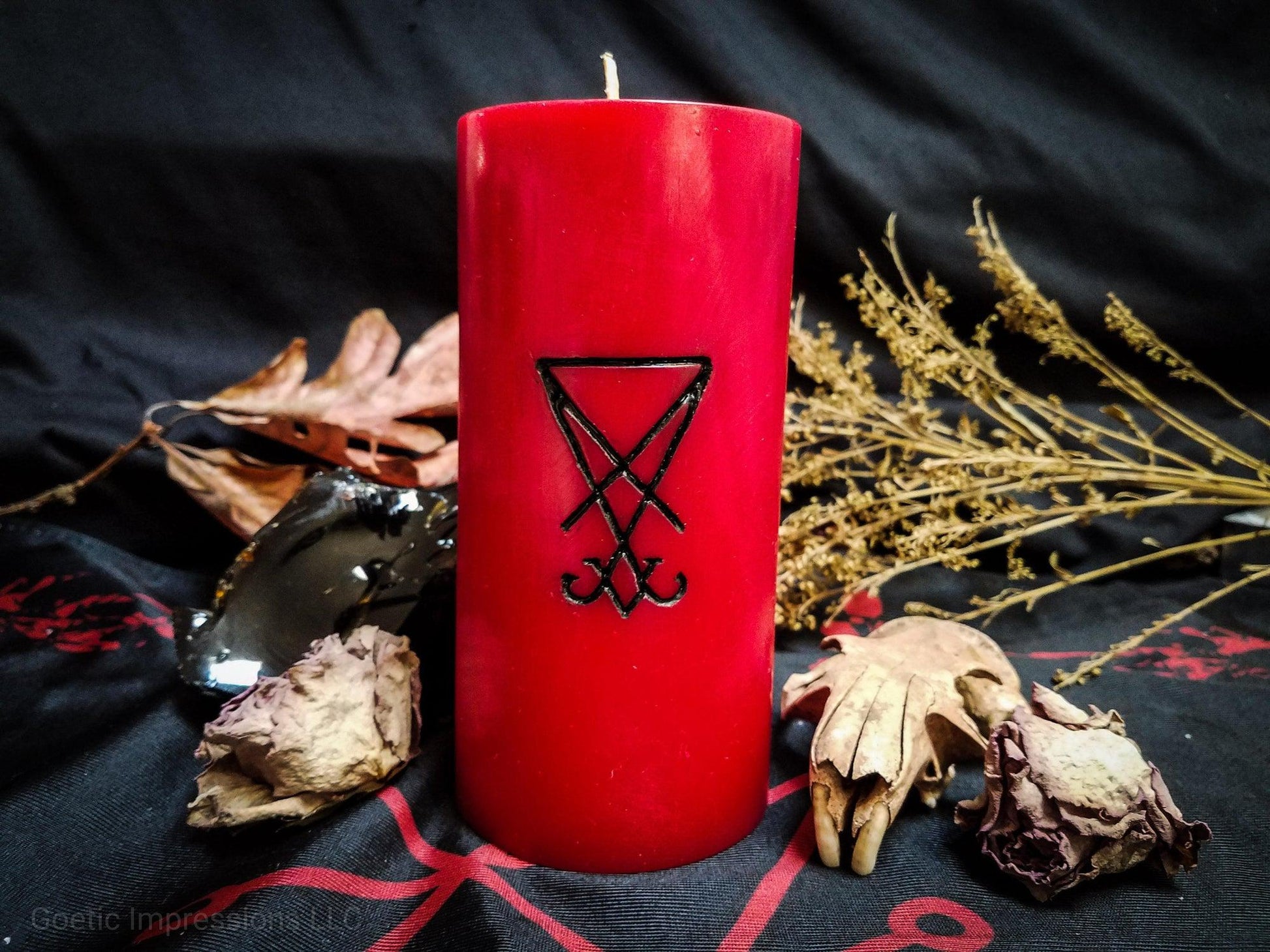 Red pillar candle with a black Lucifer sigil carved into it.