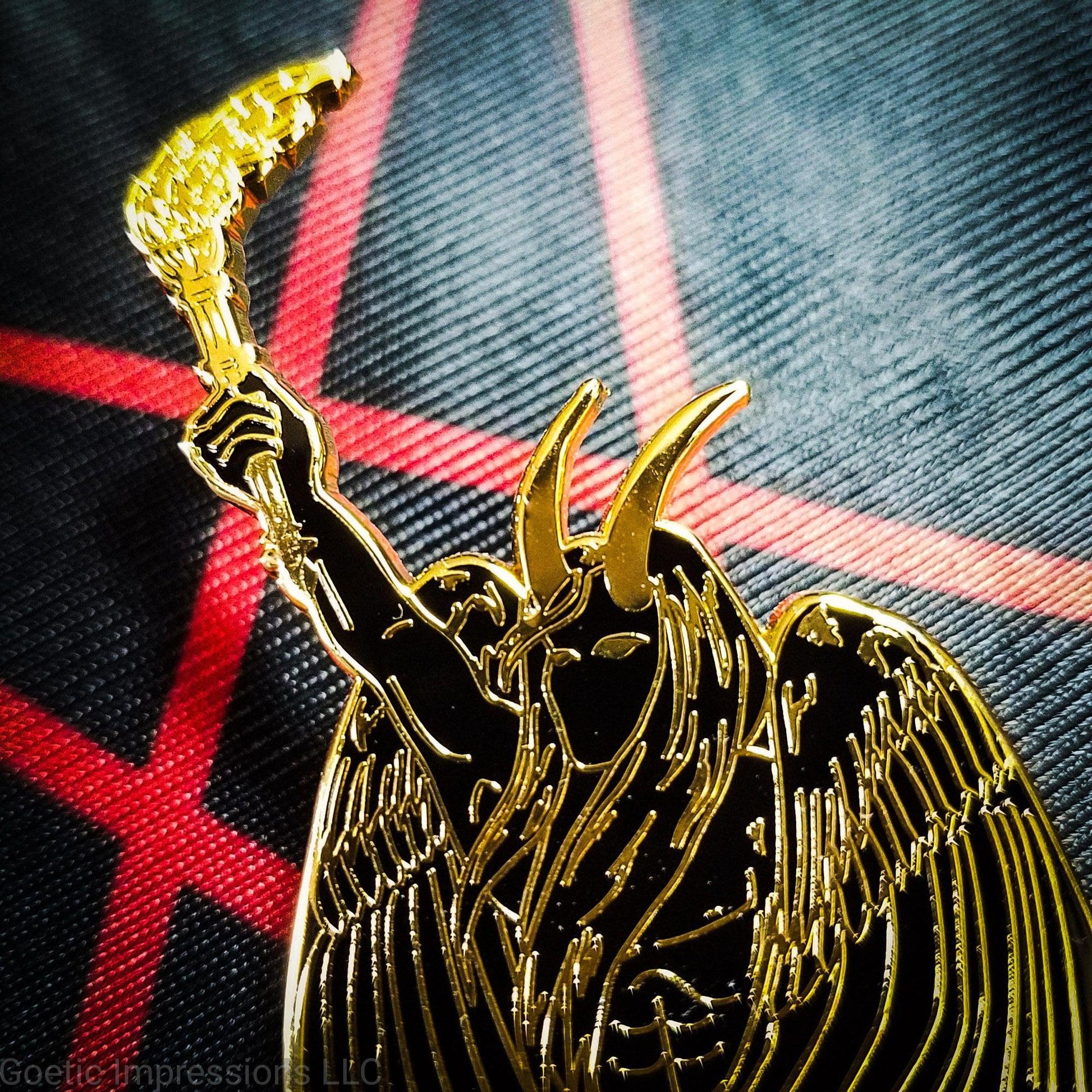 A black and gold hard enamel pin of Lucifer. Lucifer is holding a flaming torch held high and has his wings surrounding him. He has horns and is bare chested. The pin is on a red and black altar cloth with Lucifer's sigil on it. 