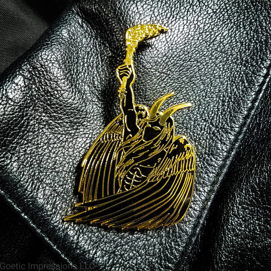 A black and gold hard enamel pin of Lucifer. Lucifer is holding a flaming torch held high and has his wings surrounding him. He has horns and is bare chested. The pin is on a black leather jacket.
