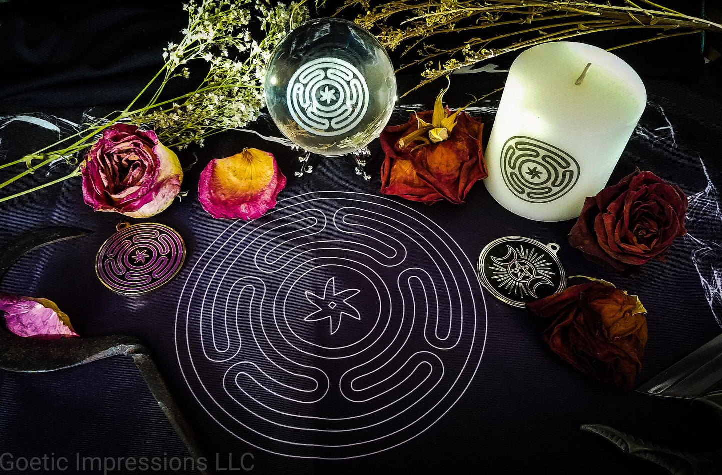 An altar with vrarious ritual tools featuring the Stropholos or Wheel of Hecate. The sigil is printed on a black and purple altar cloth. On the cloth is a white candle, a crystal ball and a gold medallion featuring the sigil. Roses and other dried herbs are decorated around the altar.