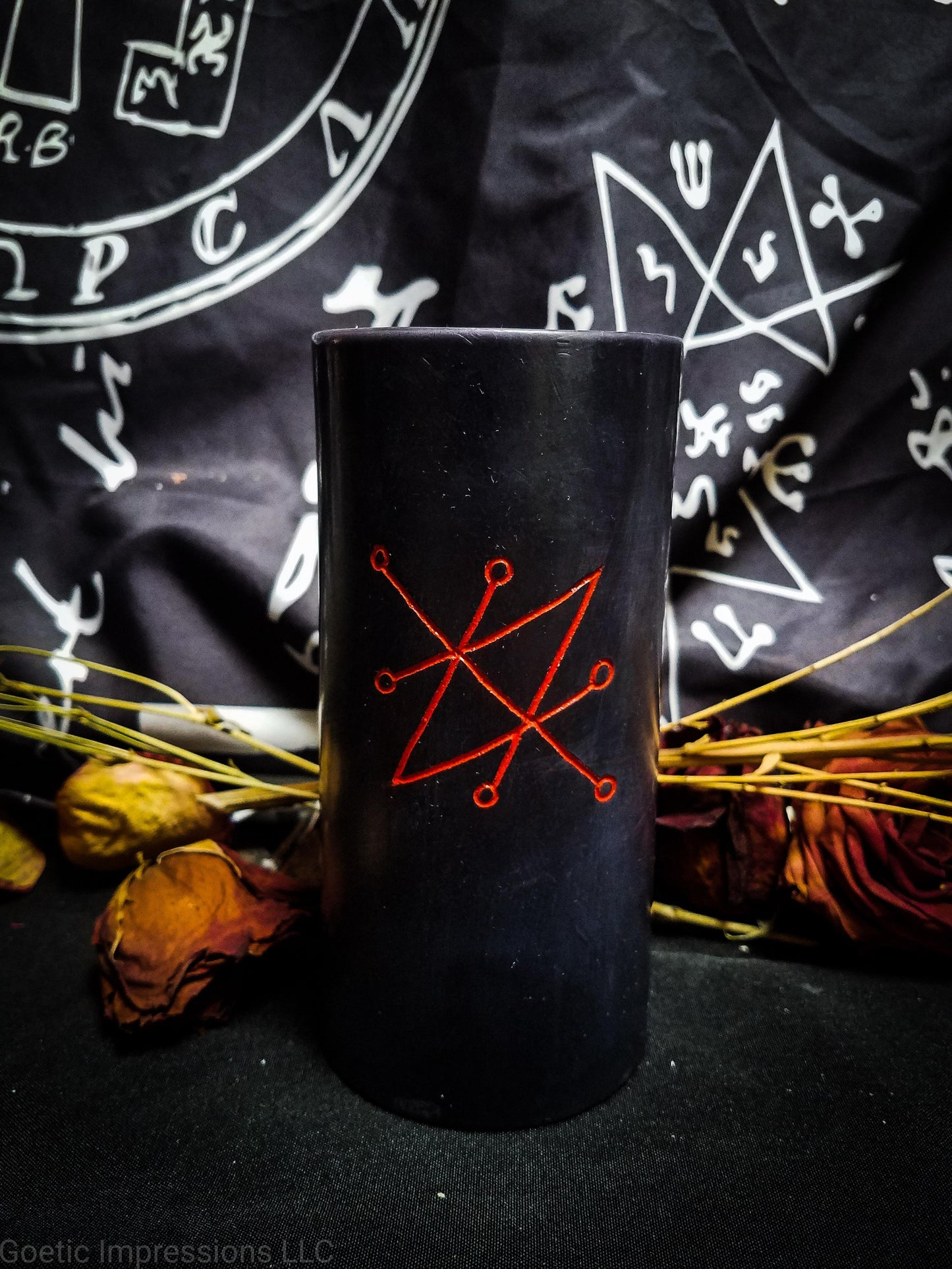 Black pillar candle featuring a red sigil of Saturn or Azazel.