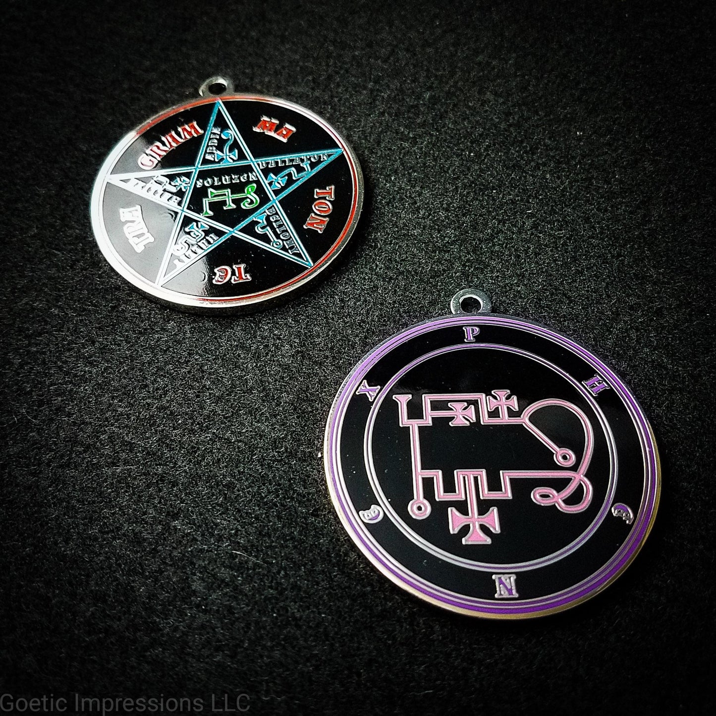 Two silver plated medallions featuring the front and back of the Ars Goetia spirit Phenex. The sigil is pink with the name and circle surrounding in purple. The Reverse is the TETRAGRAMMATON. The pentacle is blue with a red circle. Tetragrammaton is in red. The center sigil is green. 
