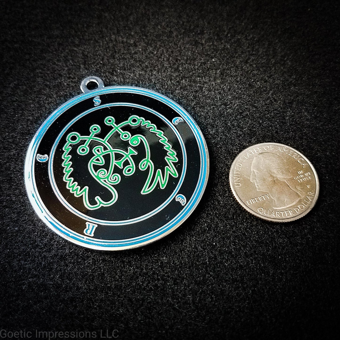 Seal of Seere next to a quarter.  The seal medallion measures two inches in diameter. The sigil is green with blue letters and circles on a black background. 