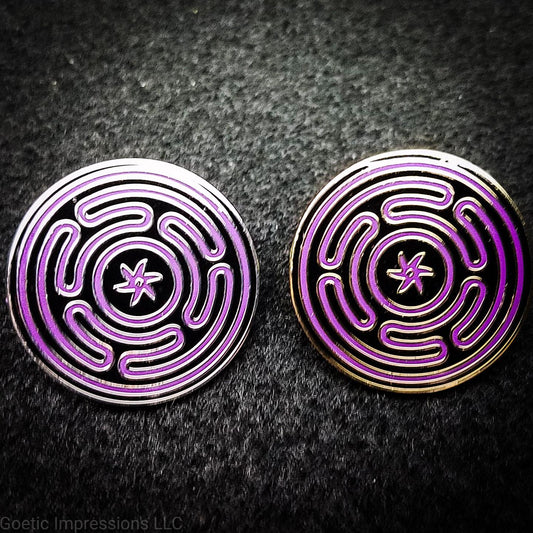 Two hard enamel pins featuring the Strophlos or Wheel of Hecate sigil. The sigil itself is colored in purple on a black background. The pins come in silver or gold plating.