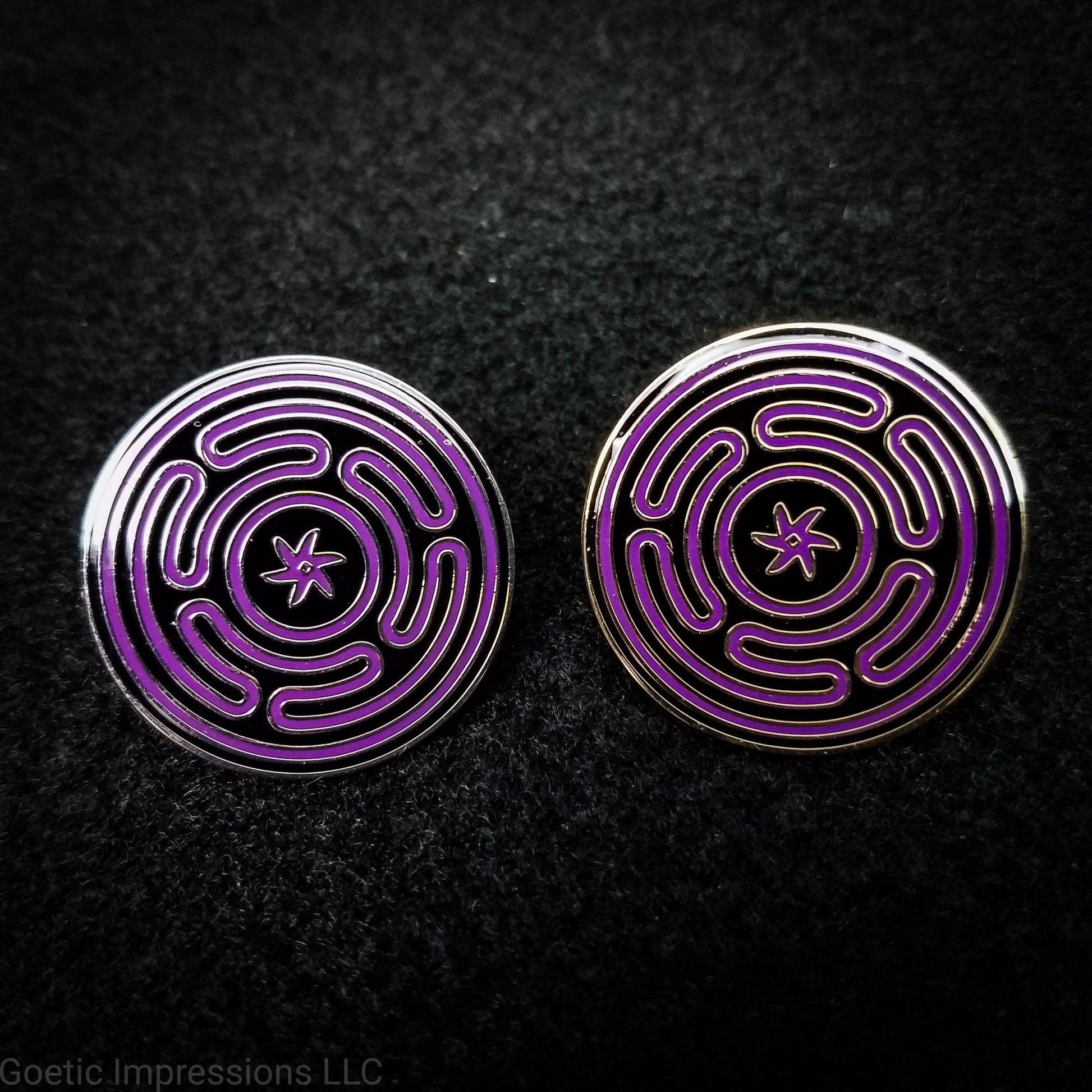 Two hard enamel pins featuring the Strophlos or Wheel of Hecate sigil. The sigil itself is colored in purple on a black background. The pins come in silver or gold plating.