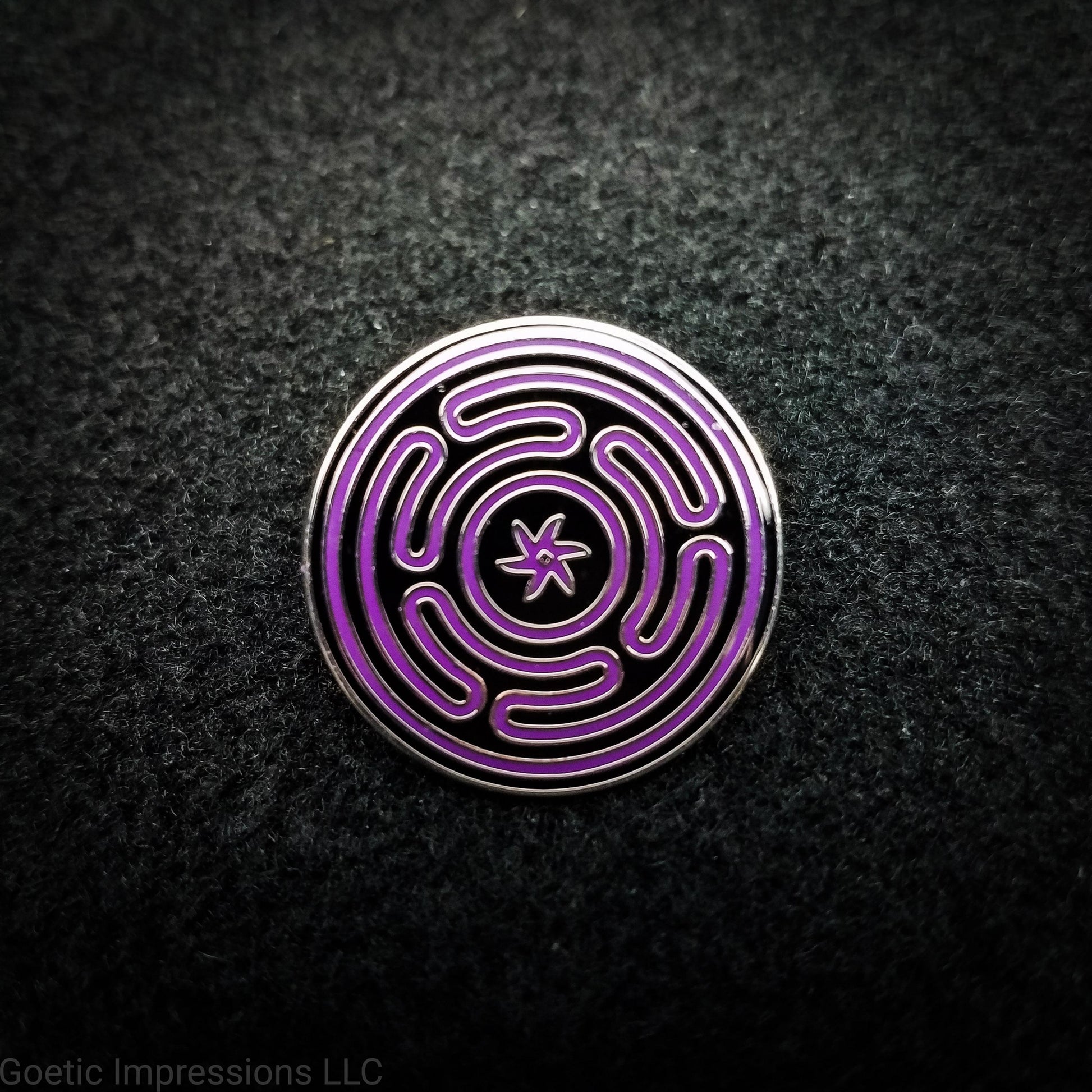A silver plated hard enamel Hecate sigil pin. The sigil is purple on a black background with a silver plated outline.