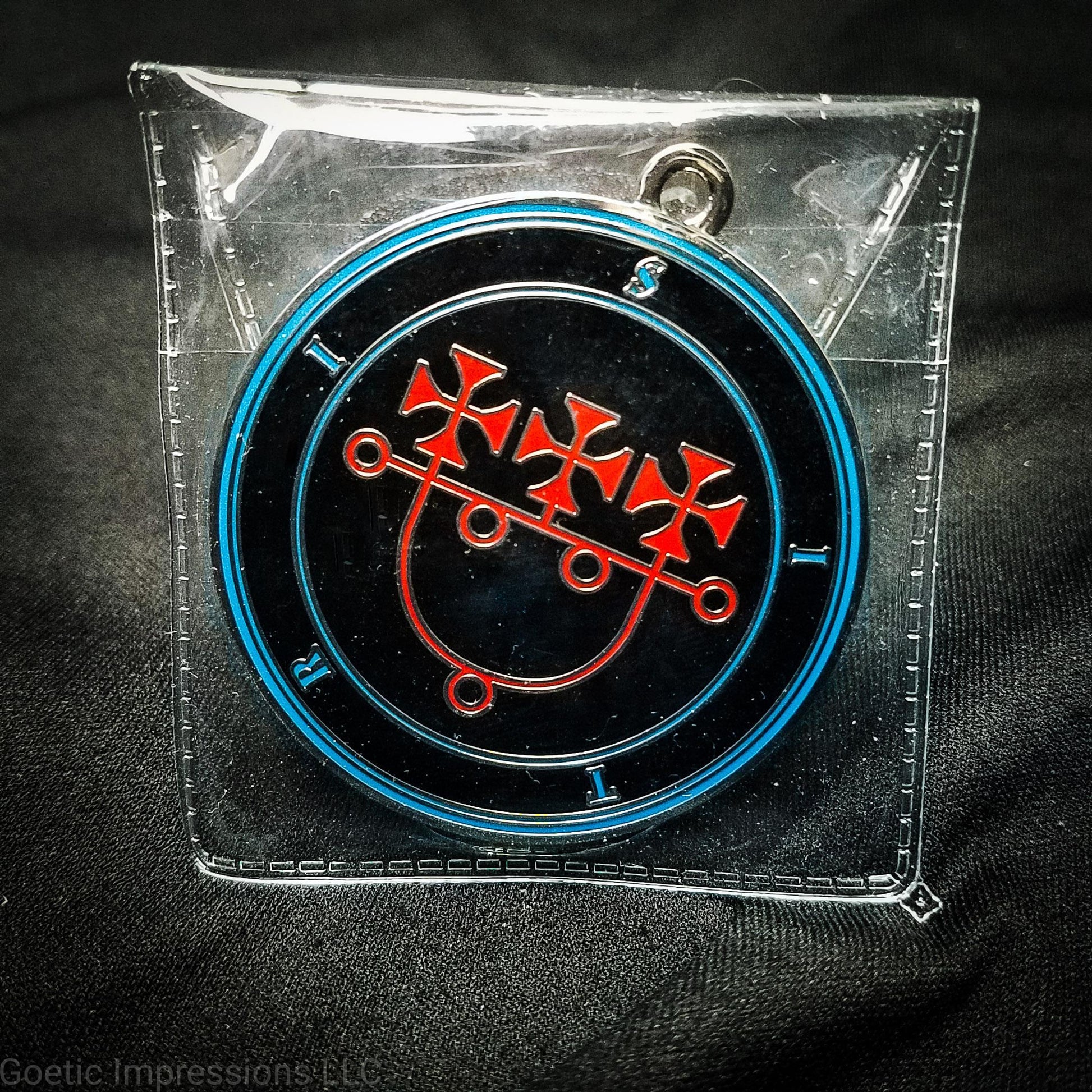 Medallion of the Ars Goetia spirit sitri. The sigil is red with blue circles and text on a black background. The medallion is silver.