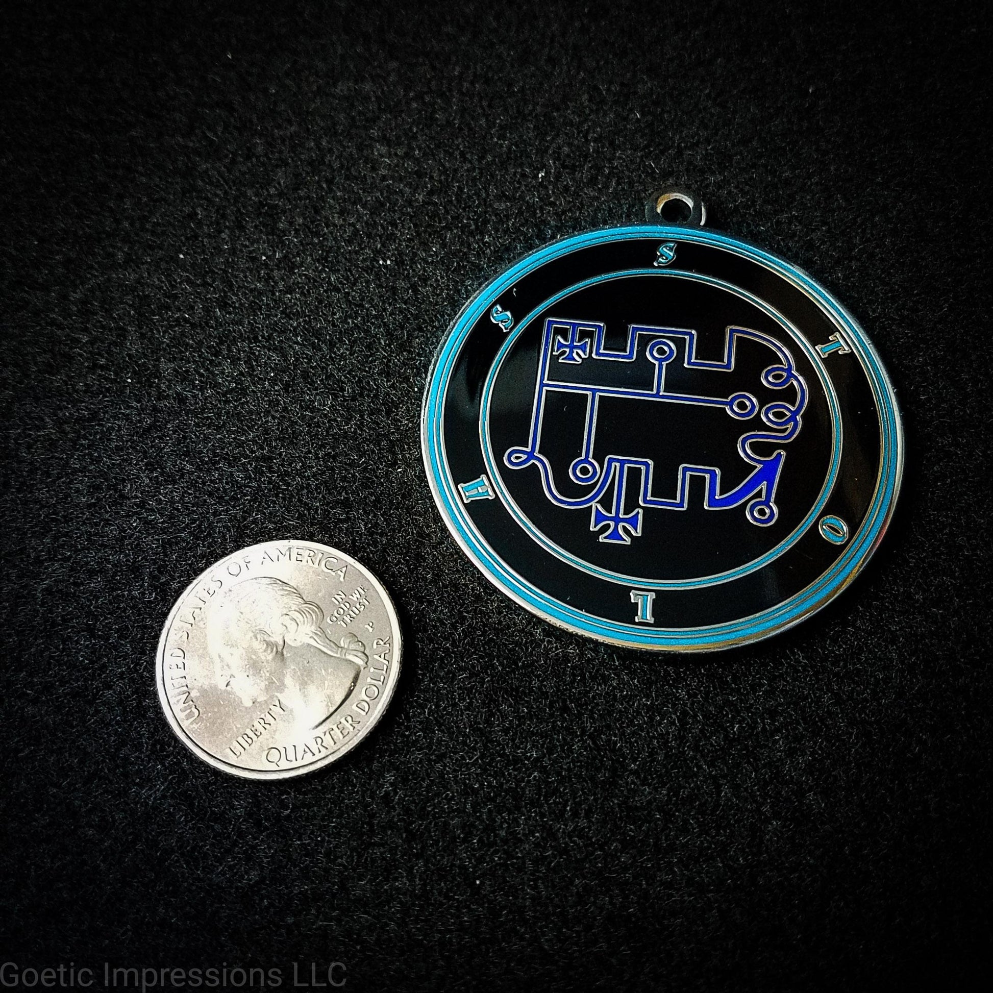 Seal of Stolas next to a quarter. The seal medallion measures two inches in diameter. The sigil is dark blue with teal letters and circles on a black background.