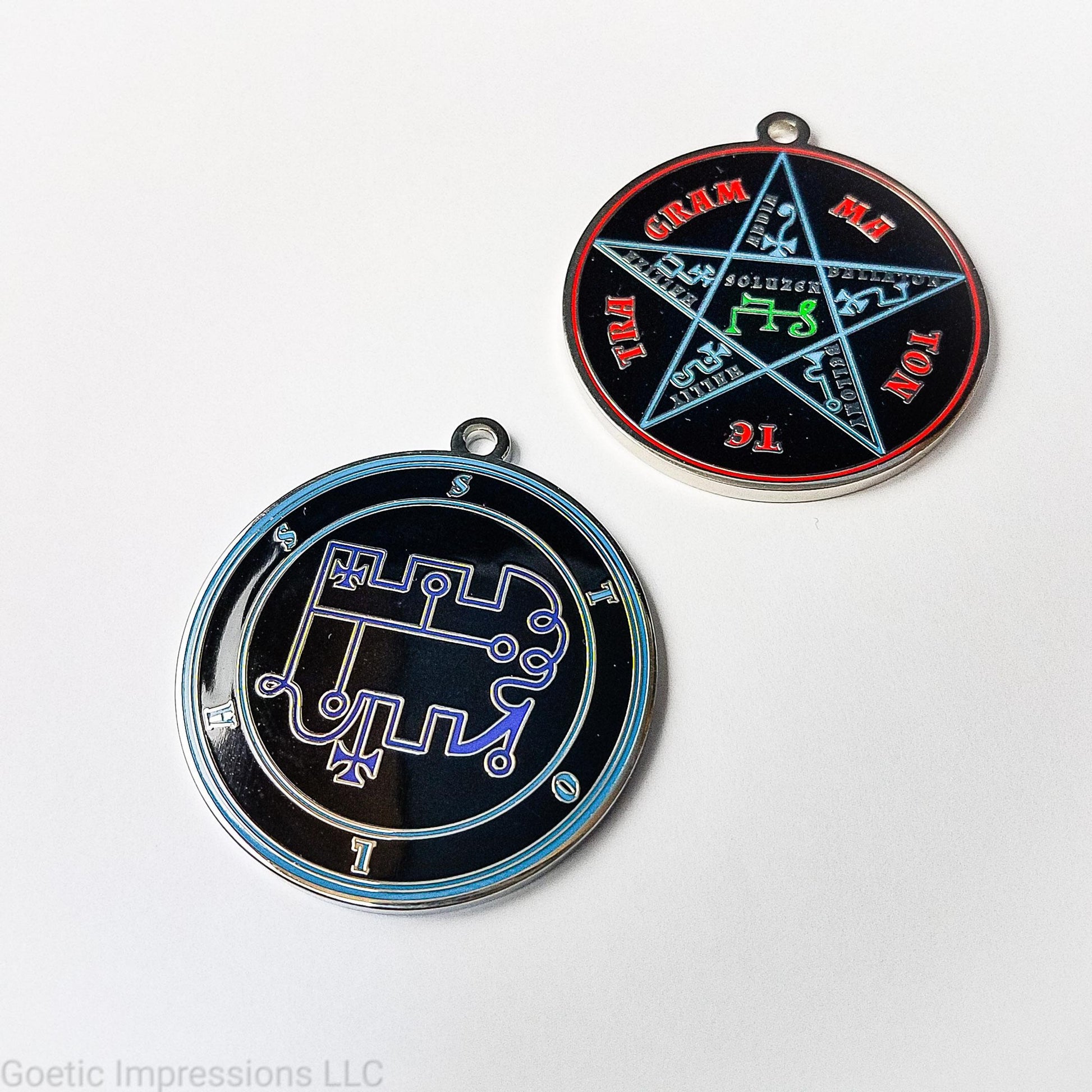 Two medallions featuring the front and back of the Ars Goetia spirit Stolas. The sigil is dark blue with the name and circle surrounding in teal. The Reverse is the TETRAGRAMMATON. The pentacle is blue with a red circle. Tetragrammaton is in red. The center sigil is green. The seal is plated in silver.