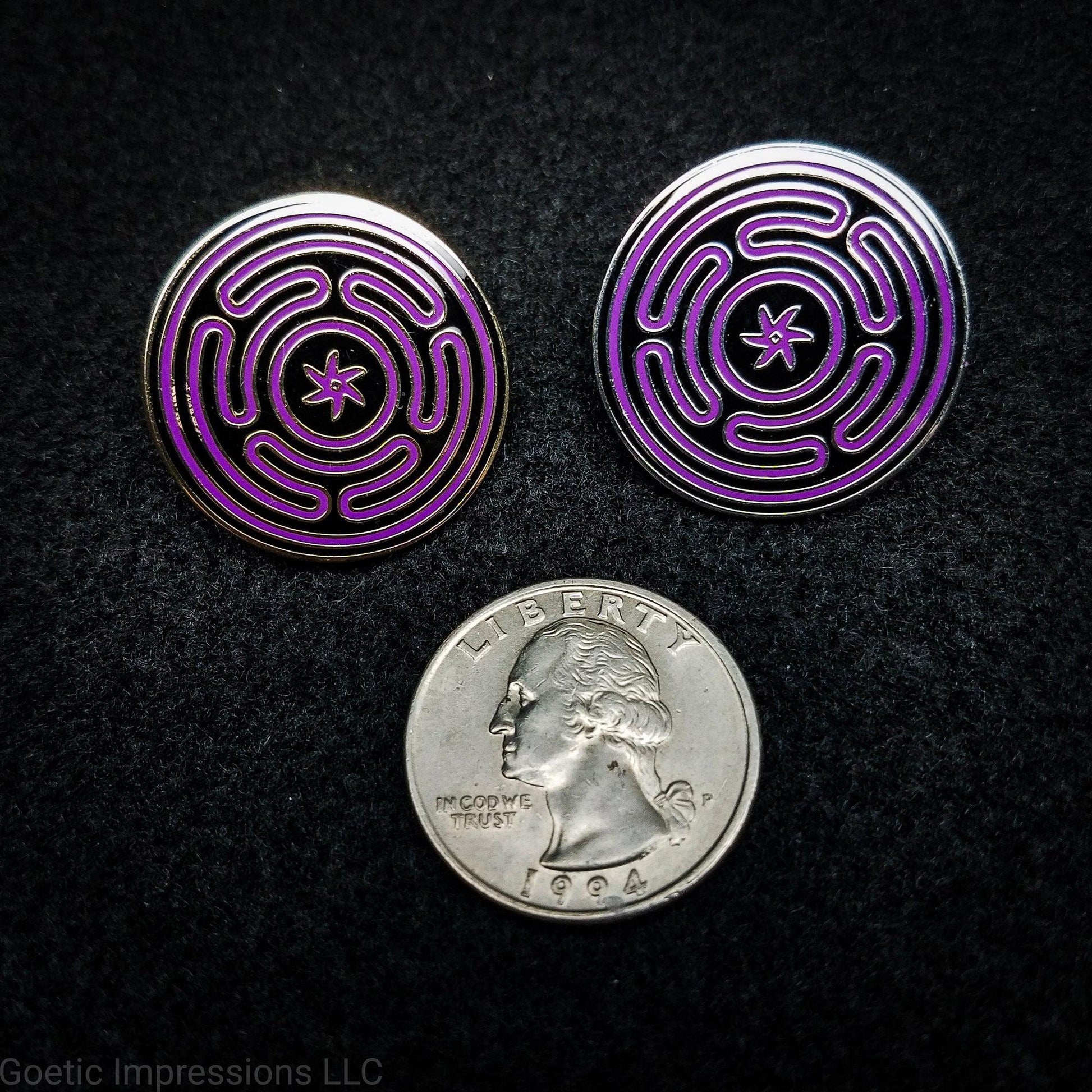 Two hard enamel pins featuring the Strophlos or Wheel of Hecate sigil. The sigil itself is colored in purple on a black background. The pins come in silver or gold plating. The pins are the same size as a quarter.
