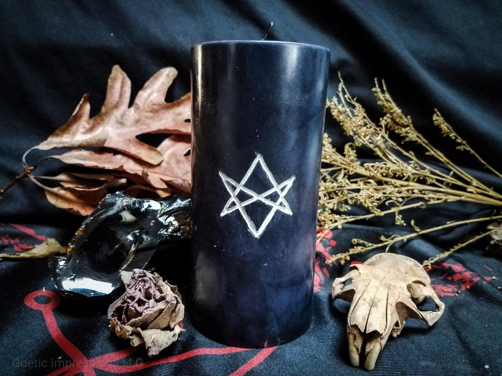 Black pillar candle with white unicursal hexagram sigil carved into it.