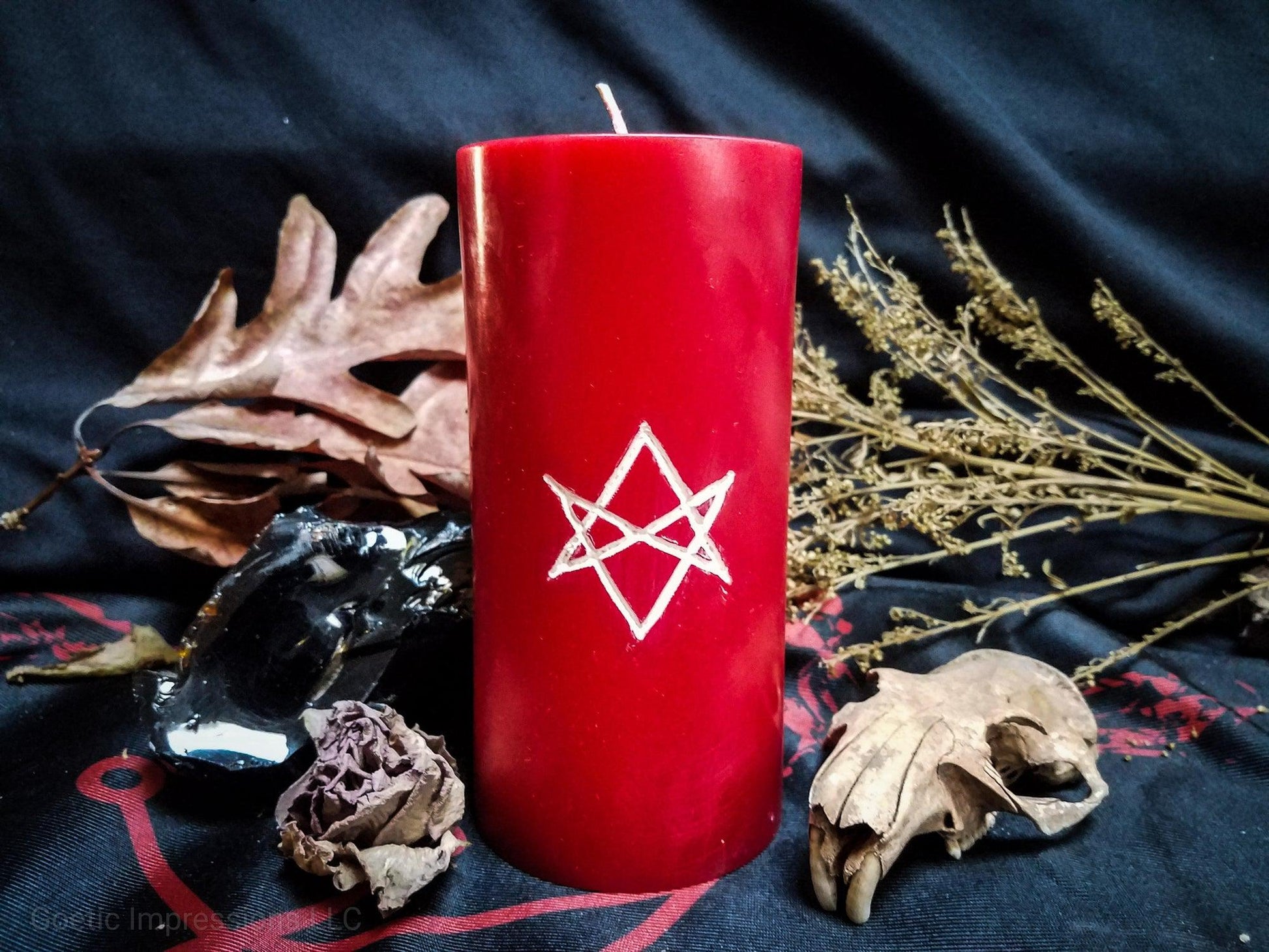Red pillar candle with white unicursal hexagram sigil carved into it.